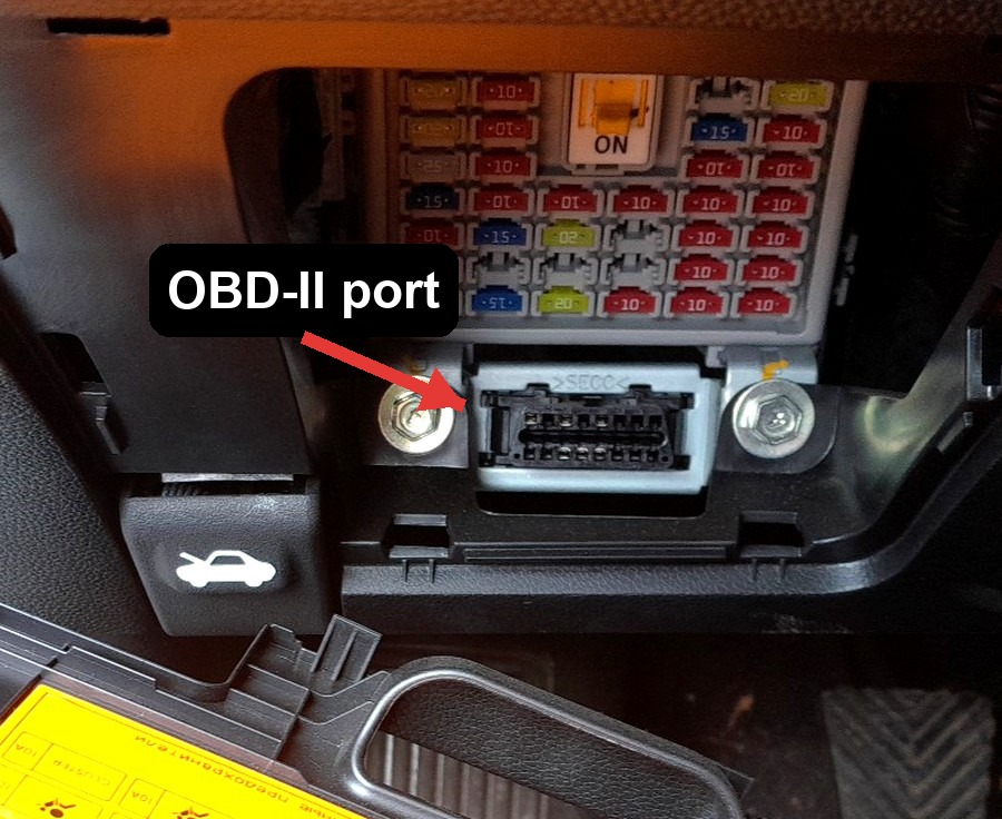 OBD-II port location on a Hyundai i20 (GB, 2014-2020), below the fuse panel in the driver's footwell