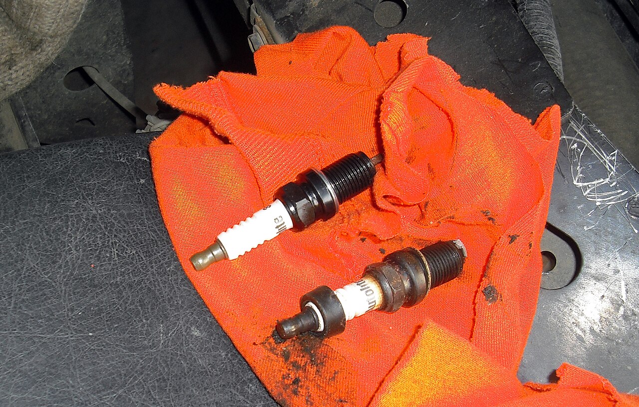 A worn used spark plug next to a new spark plug for comparison
